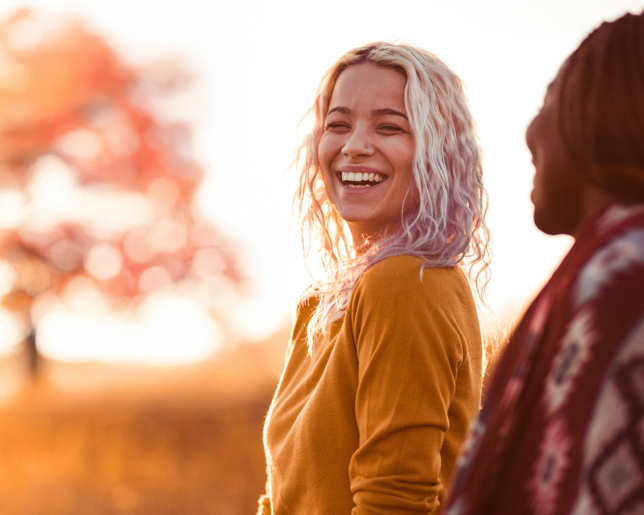 Two female friends smiling as as they talk outside